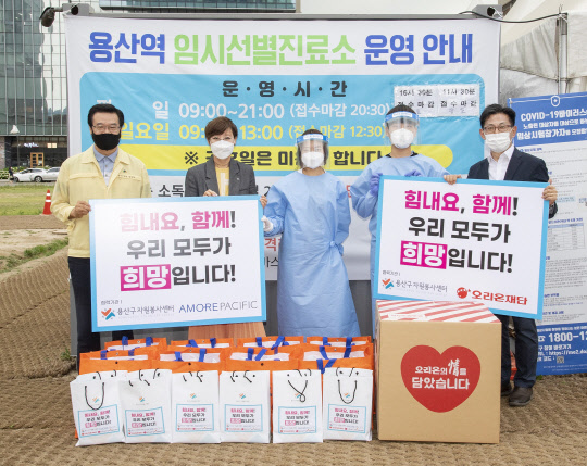 아모레퍼시픽 관계자 등이 용산 지역 의료진에게 홍삼세트를 전달하고 있다. 사진은 성장현 용산구청장(왼쪽부터), 오정화 아모레퍼시픽 지속가능디비전장, 용산구 의료진 2명, 김부곤 오리온재단 수석부장. <아모레퍼시픽 제공>